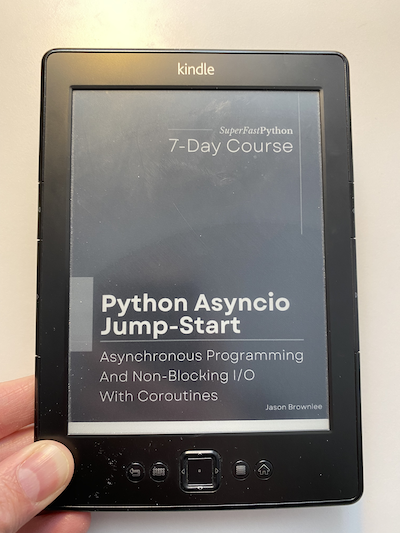 Photo of me holding my kindle showing a copy of "Python asyncio Jump-Start"